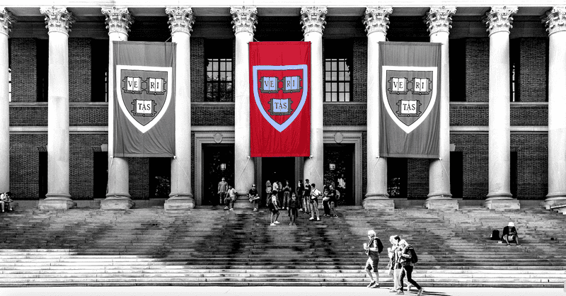 A black and white image of the Widener Library at Harvard University showing three banners with the words "Veritas." The middle banner is a crimson red.